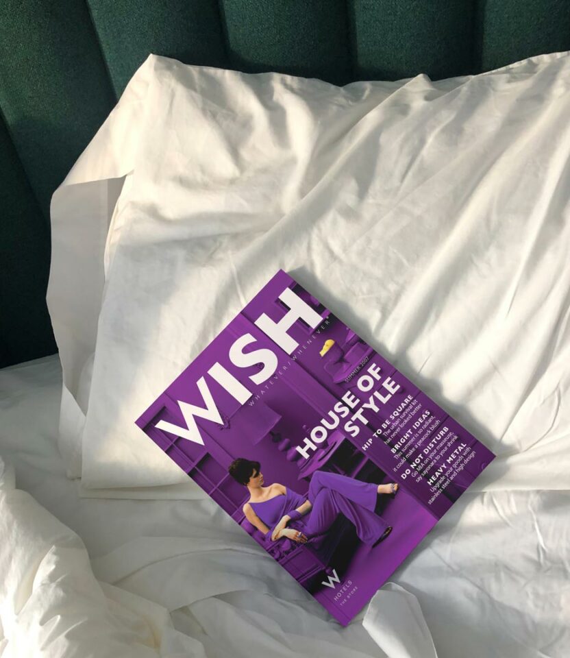 W Hotels WISH magazine by PlanetFab displayed on hotel bedding, featuring luxury offerings