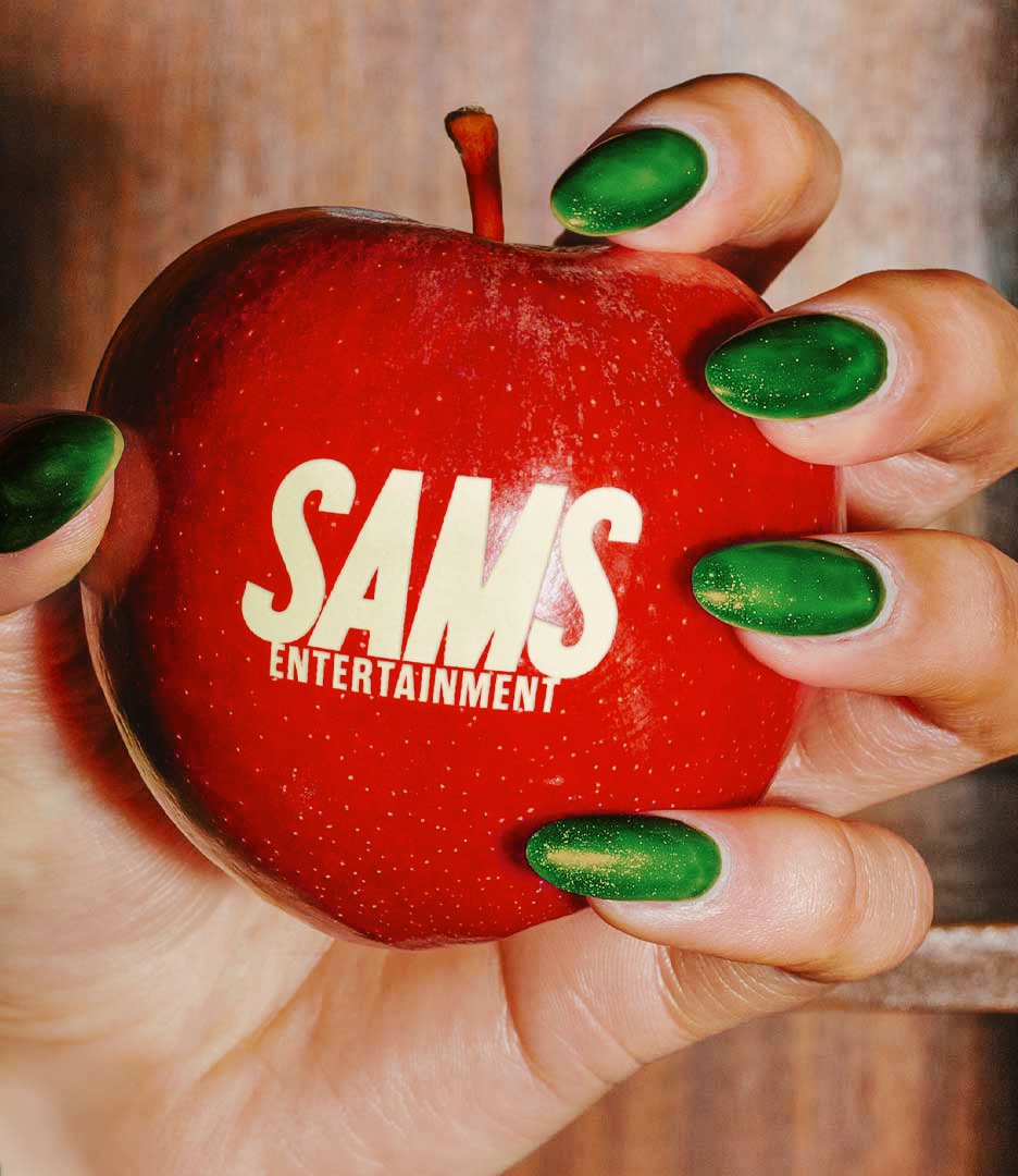 Red apple with Sams Entertainment logo held by hand with green nails