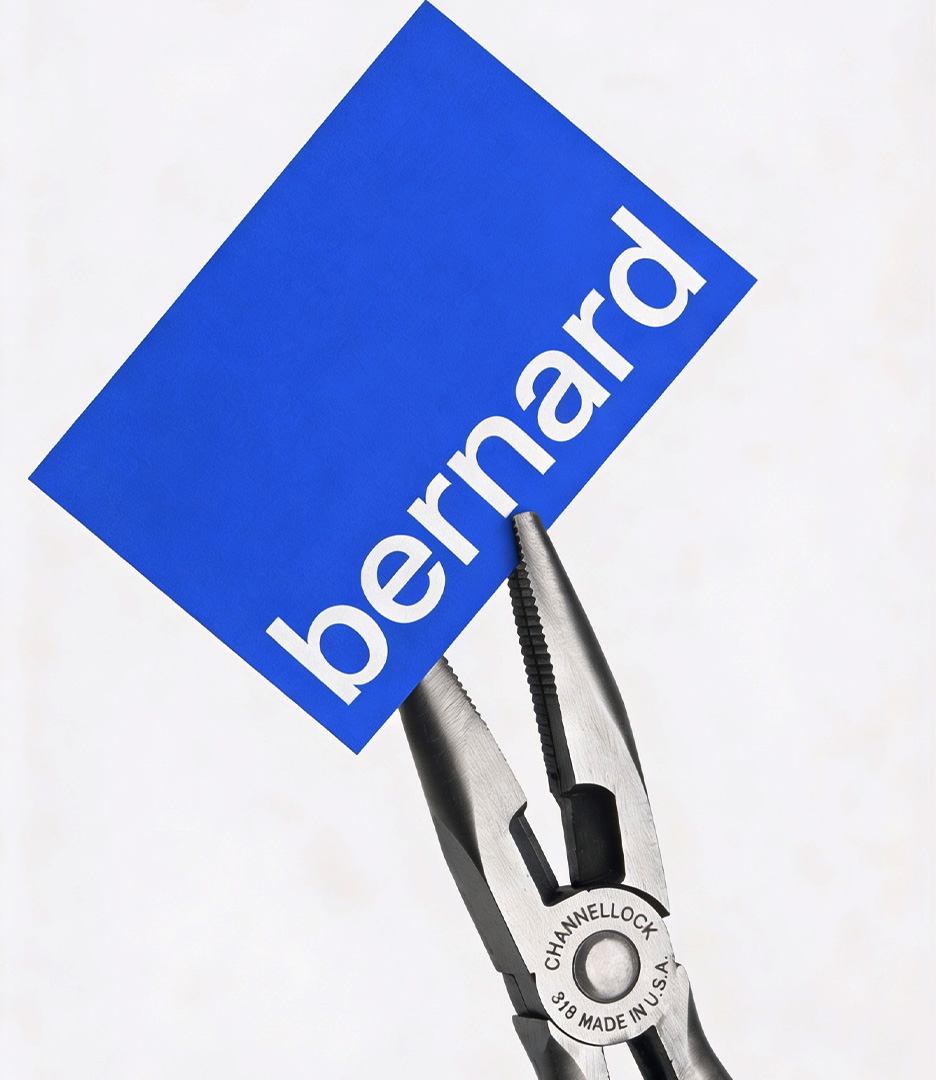Channellock pliers gripping a royal blue business card printed with the Bernard wordmark in white. Bernard AI brand identity by PlanetFab.