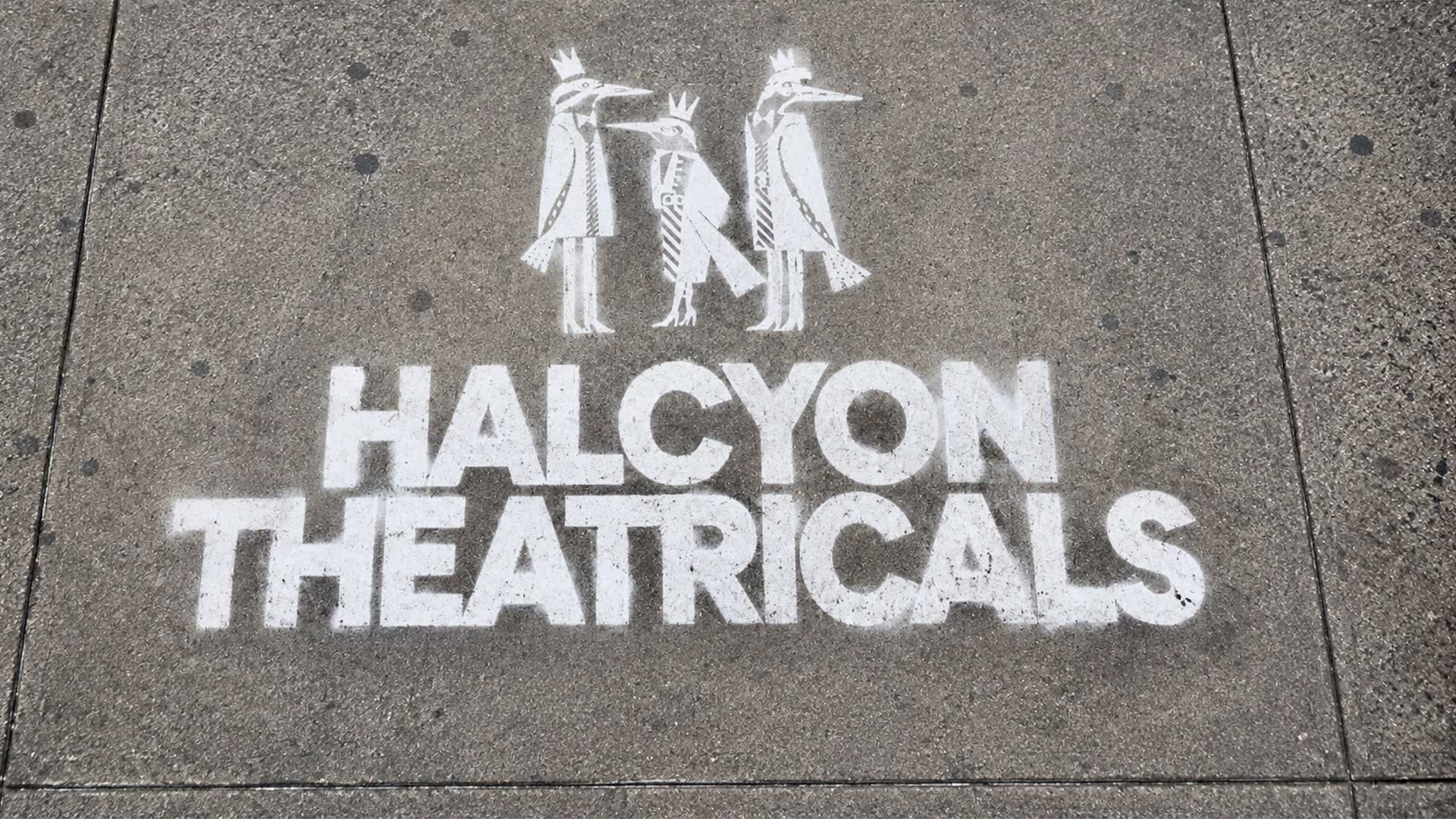 Halcyon Theatricals logo and three-bird emblem stenciled in white on a city sidewalk.